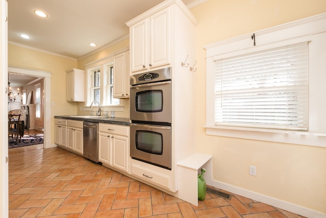 kitchen with baseboards, visible vents, stainless steel appliances, crown molding, and a sink