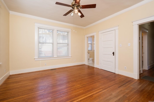 empty room with wood finished floors, visible vents, baseboards, a ceiling fan, and crown molding