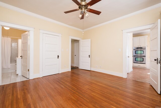 unfurnished bedroom with ornamental molding, light wood-type flooring, baseboards, and ensuite bathroom