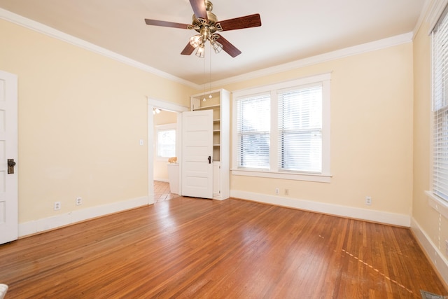 empty room with baseboards, wood finished floors, and crown molding