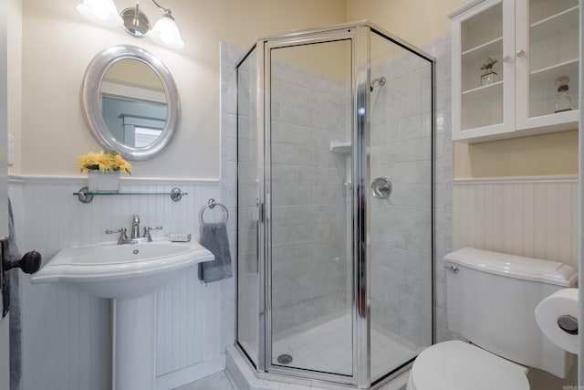 bathroom with a wainscoted wall, a shower stall, and toilet