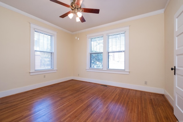 spare room with ceiling fan, wood finished floors, visible vents, baseboards, and ornamental molding