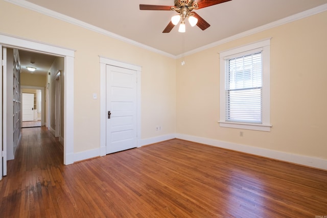 empty room with baseboards, wood finished floors, a ceiling fan, and crown molding