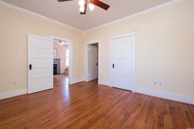 unfurnished room featuring ornamental molding, a fireplace, and wood finished floors