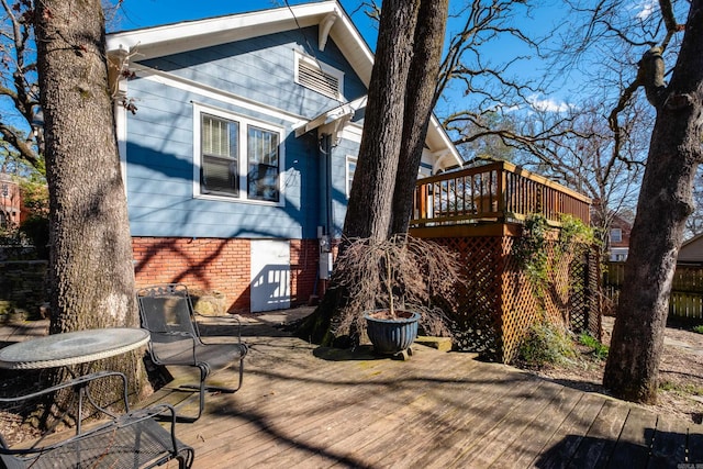 rear view of house featuring brick siding and a wooden deck