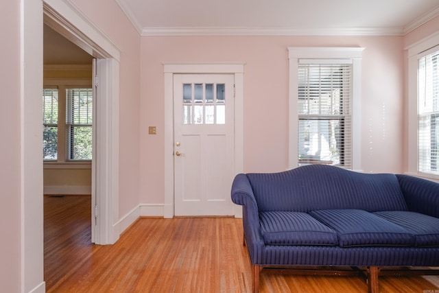 foyer entrance featuring ornamental molding, light wood-style flooring, and baseboards