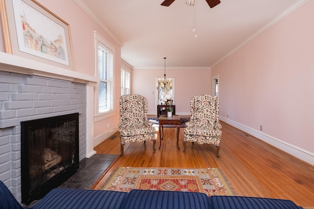 sitting room with a brick fireplace, baseboards, ornamental molding, and wood finished floors