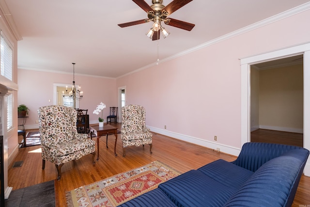 sitting room with ceiling fan with notable chandelier, crown molding, baseboards, and wood finished floors