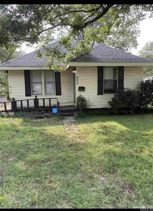 view of front of house with a shingled roof and a front yard