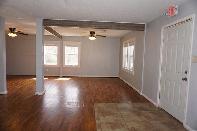 spare room featuring wood-type flooring, baseboards, a wealth of natural light, and beamed ceiling