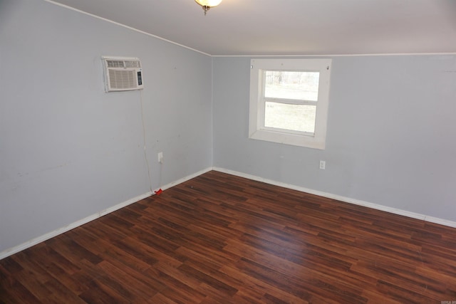 unfurnished room featuring lofted ceiling, ornamental molding, an AC wall unit, wood finished floors, and baseboards