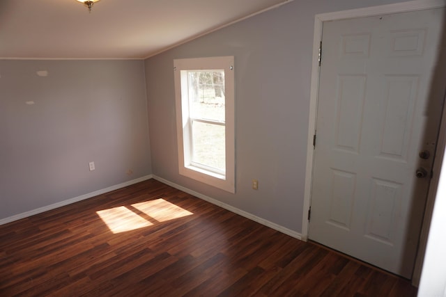 spare room featuring lofted ceiling, baseboards, and dark wood-style flooring