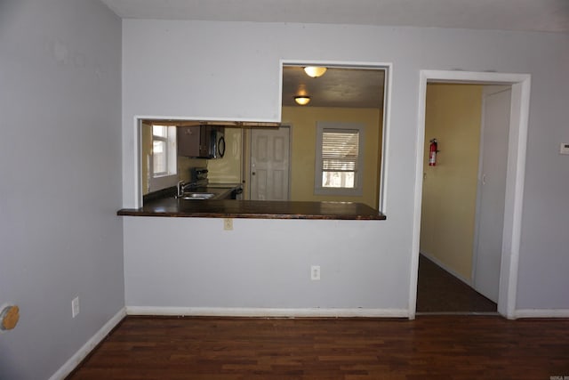 kitchen with black microwave, dark countertops, wood finished floors, and baseboards