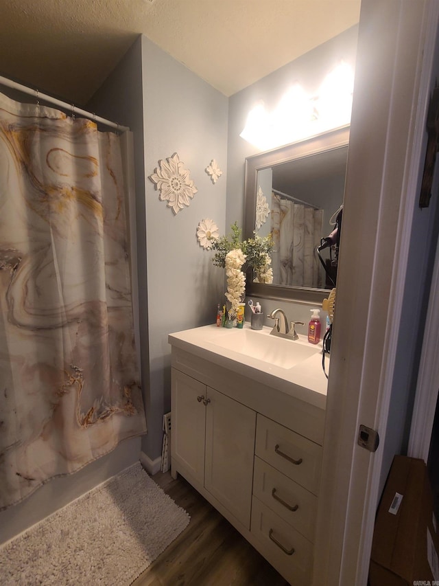 full bathroom with curtained shower, vanity, and wood finished floors