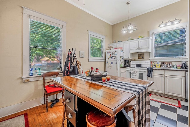 dining area with baseboards, ornamental molding, light wood-type flooring, and an inviting chandelier