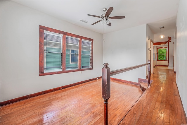 unfurnished room with a ceiling fan, light wood-type flooring, visible vents, and baseboards