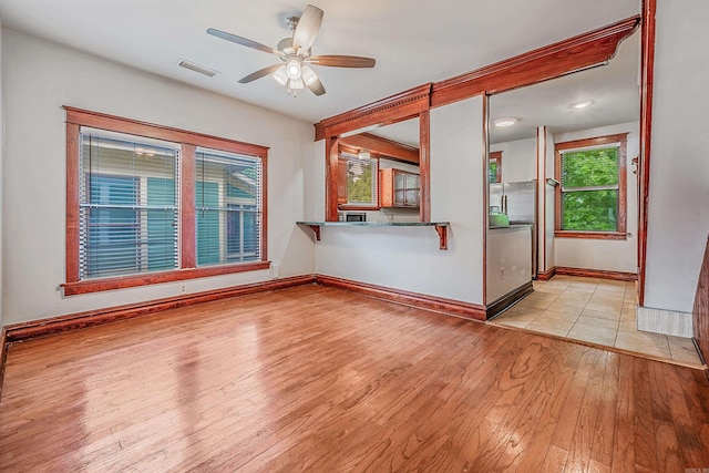 empty room with light wood-style flooring, visible vents, ceiling fan, and baseboards