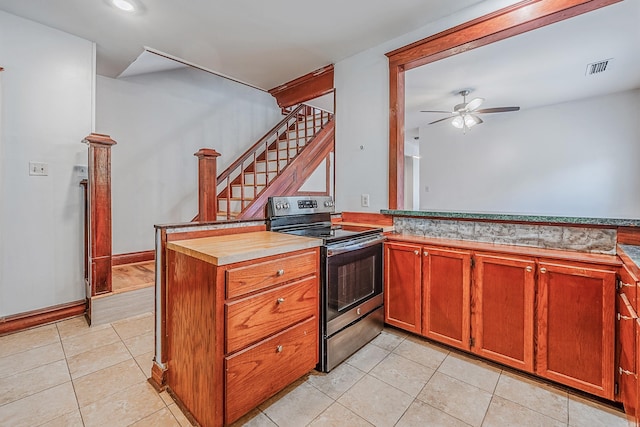 kitchen featuring light tile patterned floors, visible vents, a ceiling fan, electric stove, and a peninsula