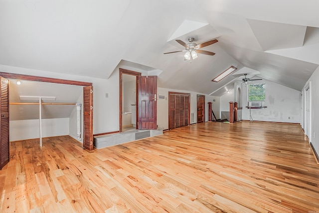 additional living space with lofted ceiling with skylight, cooling unit, and wood finished floors