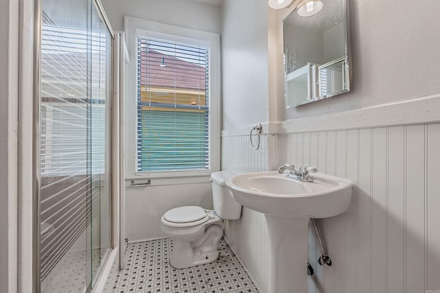 full bath with a wainscoted wall, a sink, a shower stall, and toilet