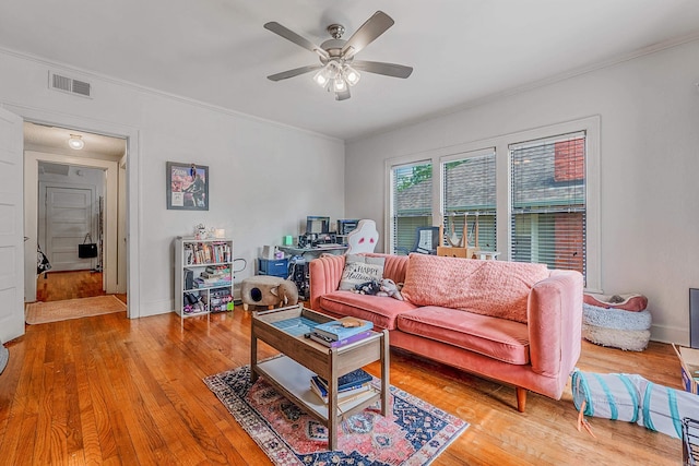 living area with ceiling fan, visible vents, baseboards, ornamental molding, and light wood-type flooring