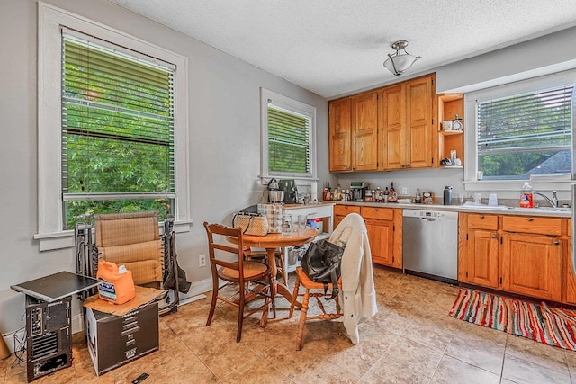 kitchen featuring light countertops, plenty of natural light, a textured ceiling, and stainless steel dishwasher