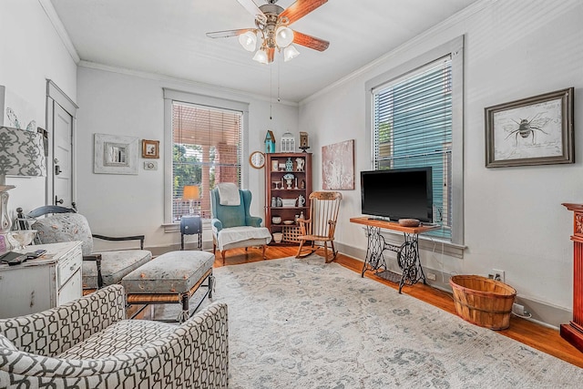 living area featuring baseboards, crown molding, a ceiling fan, and wood finished floors