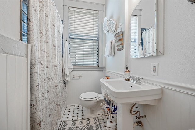 bathroom featuring a shower with curtain, wainscoting, toilet, and tile patterned floors