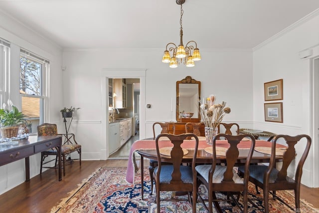 dining room with ornamental molding, wood finished floors, and a notable chandelier