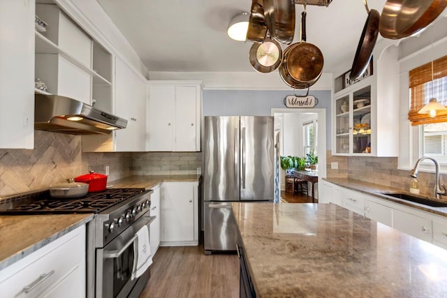 kitchen with appliances with stainless steel finishes, a healthy amount of sunlight, a sink, and white cabinetry