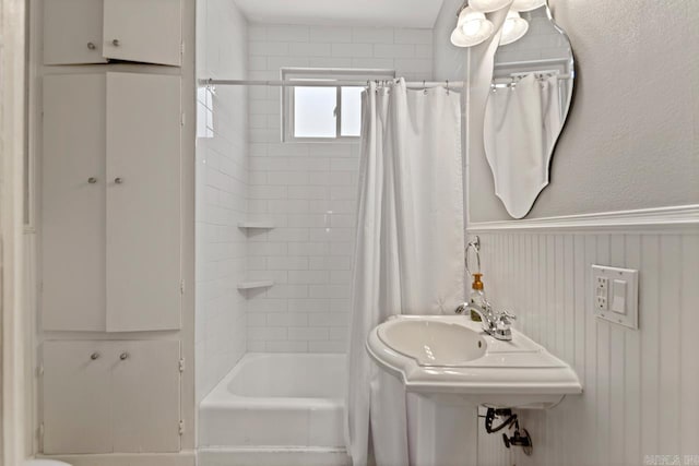 bathroom featuring shower / tub combo and wainscoting