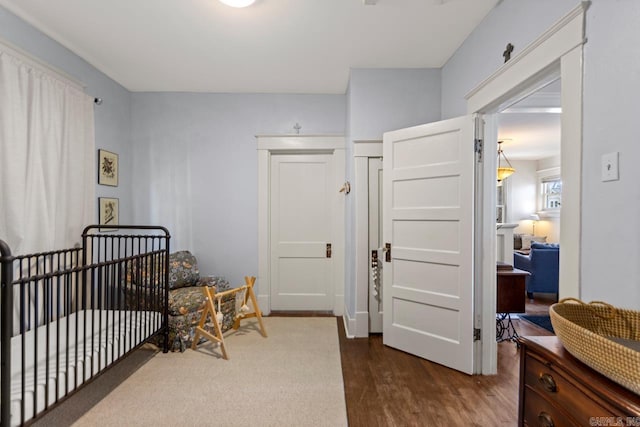 bedroom with a nursery area and dark wood finished floors