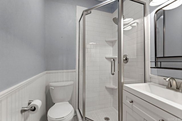 bathroom featuring a wainscoted wall, a shower stall, and toilet