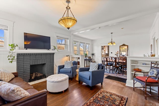 living room featuring a notable chandelier, a fireplace, and wood finished floors