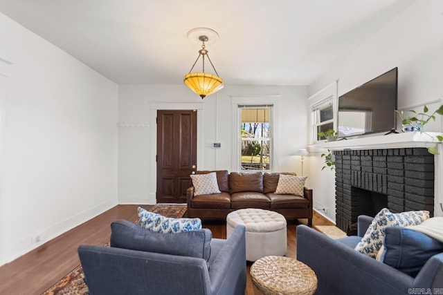 living area with a brick fireplace, baseboards, and wood finished floors