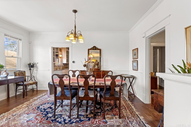 dining space featuring a chandelier, ornamental molding, wood finished floors, and baseboards