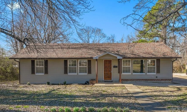 ranch-style home featuring roof with shingles and a front lawn