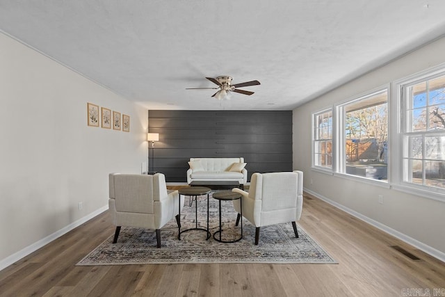 living area with wood finished floors, visible vents, and baseboards