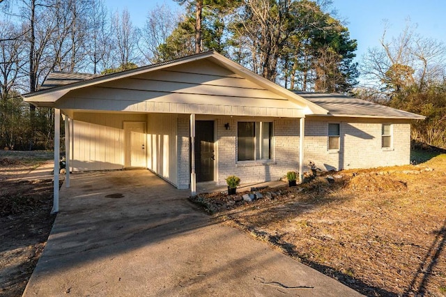 view of front of home with a carport, driveway, brick siding, and covered porch