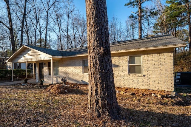 view of front of property with central AC unit, brick siding, and a porch