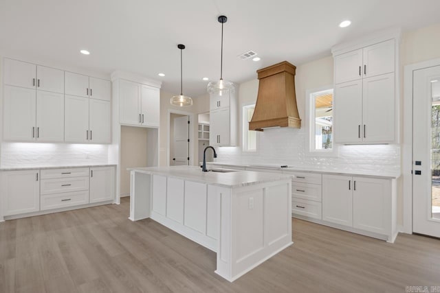 kitchen featuring light wood-style floors, custom range hood, a sink, and white cabinetry