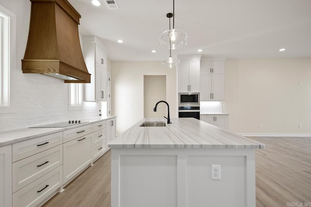 kitchen featuring tasteful backsplash, visible vents, appliances with stainless steel finishes, premium range hood, and a sink