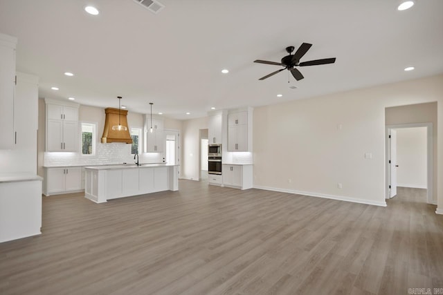 unfurnished living room with recessed lighting, a sink, visible vents, and light wood-style floors