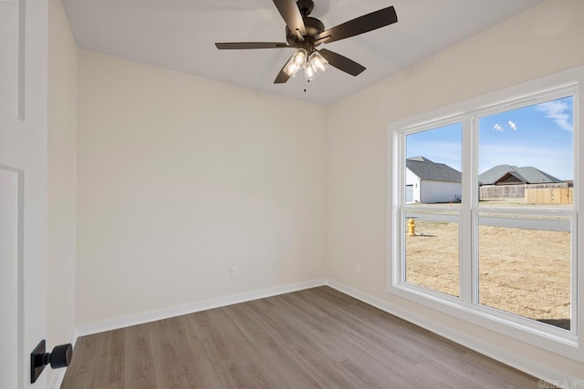 spare room featuring ceiling fan, wood finished floors, and baseboards