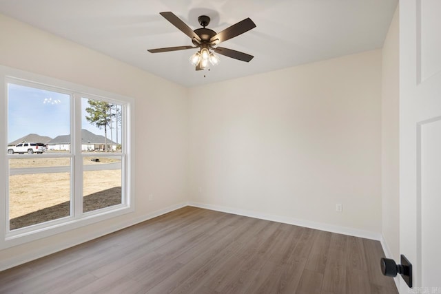 spare room featuring a ceiling fan, baseboards, and wood finished floors