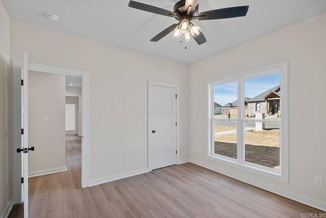 interior space featuring light wood-type flooring, baseboards, and a ceiling fan