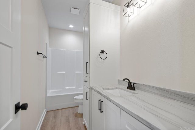 bathroom with vanity, shower / bath combination, wood finished floors, and toilet