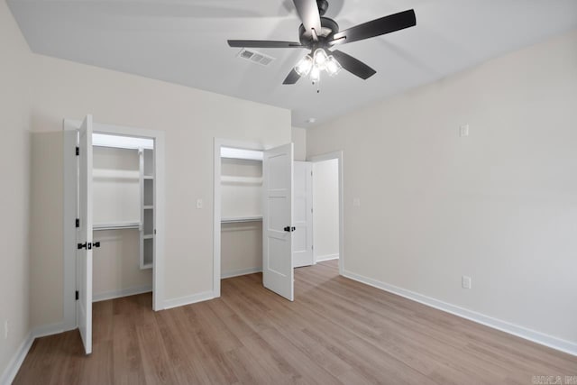 unfurnished bedroom with baseboards, visible vents, a ceiling fan, light wood-style flooring, and multiple closets