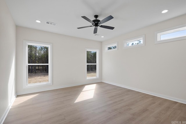 empty room with baseboards, visible vents, and light wood finished floors