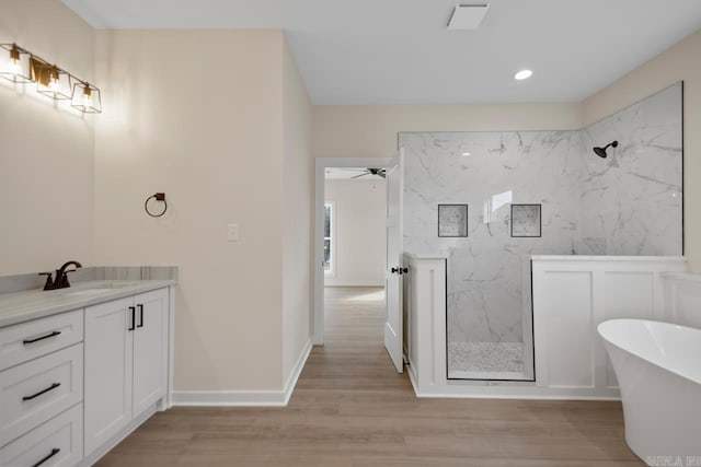 bathroom with a soaking tub, baseboards, a marble finish shower, and wood finished floors